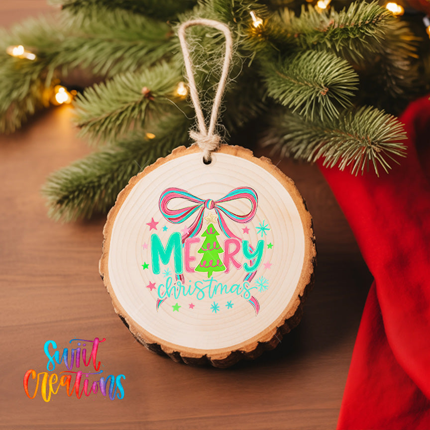 A round wooden ornament with a bow and the text "MARY christmas" is hanging on a Christmas tree, surrounded by pine branches and twinkling lights.