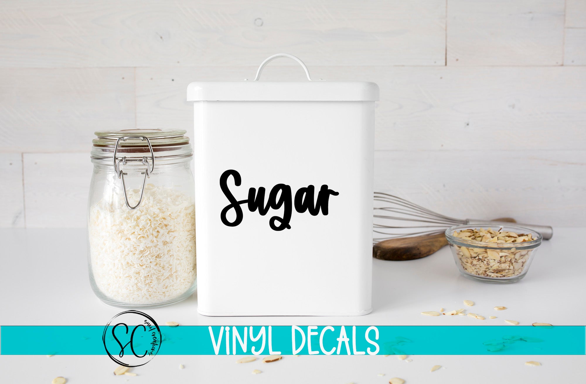 a white canister labeled "Sugar" next to a glass jar filled with white rice, a whisk, and a small glass bowl containing nuts, all placed on a white surface.