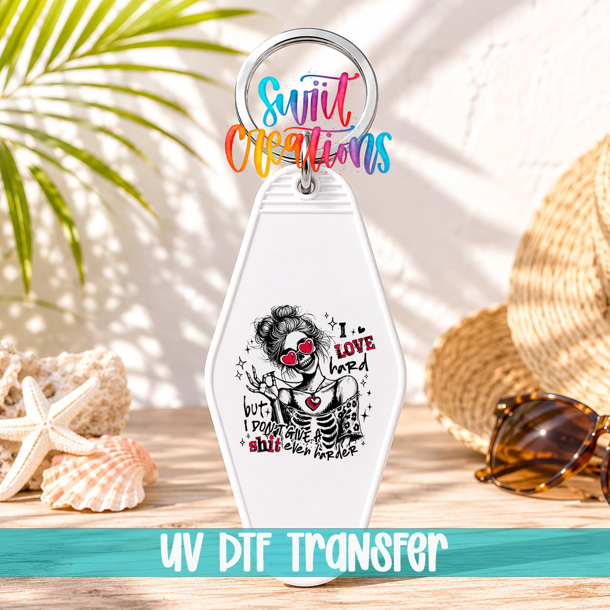A keychain with a colorful design featuring a skeleton wearing sunglasses and the text "I LOVE HARD" printed on it, placed on a wooden surface with sunglasses and seashells in the background.