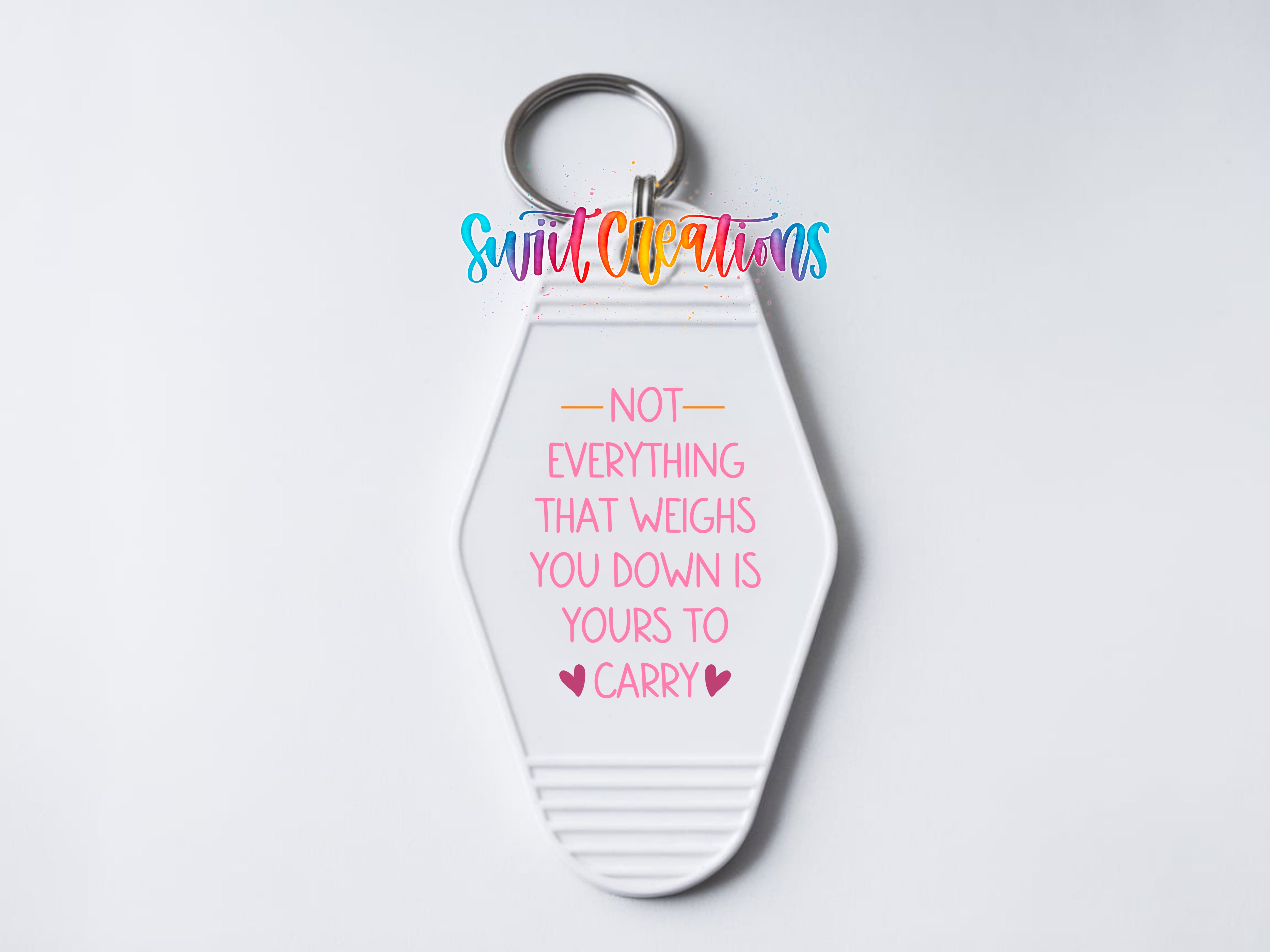 A keychain with a message that reads "NOT EVERYTHING THAT WEIGHS YOU DOWN IS YOURS TO CARRY" in pink and purple text.