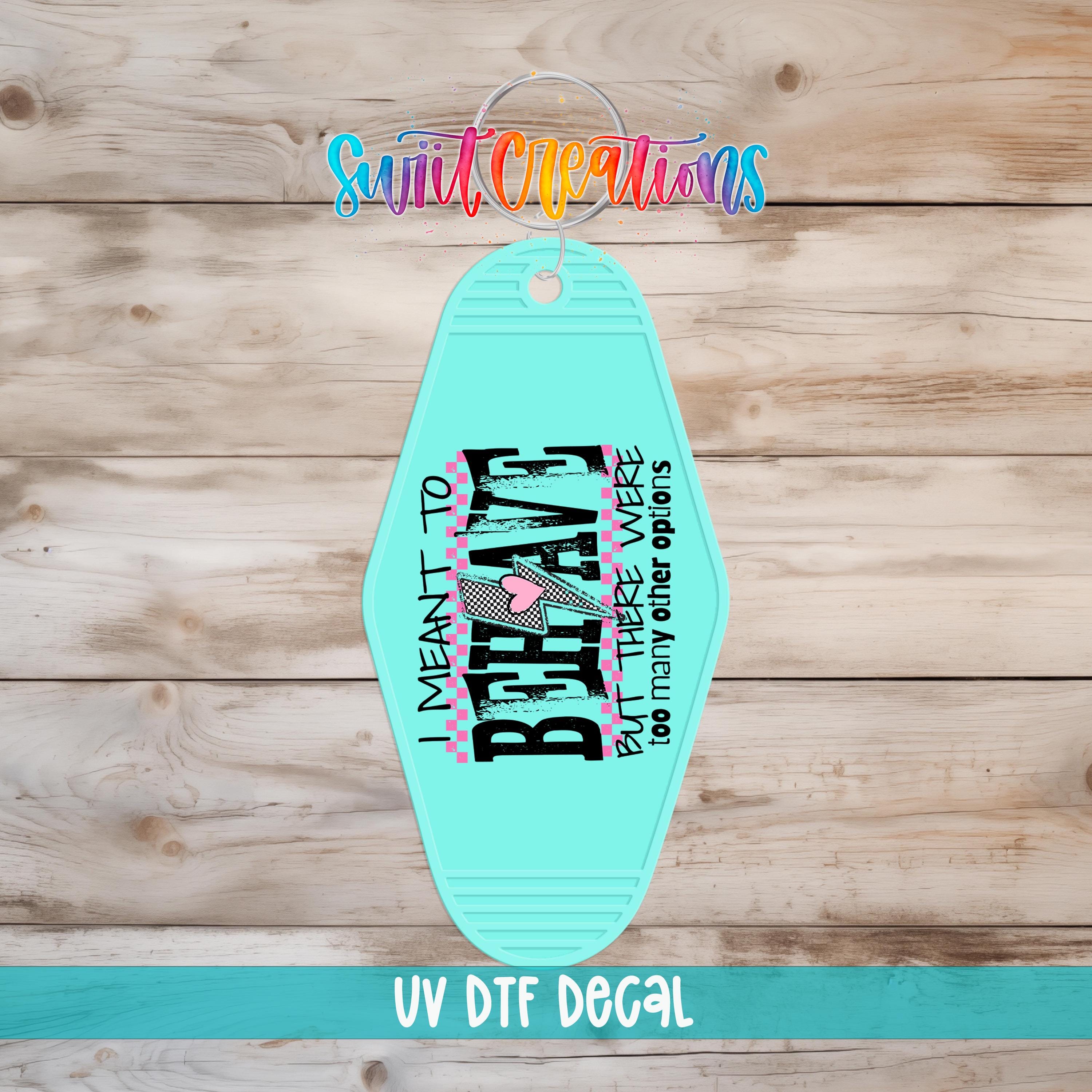 A turquoise keychain with a printed message on it, placed on a wooden surface.