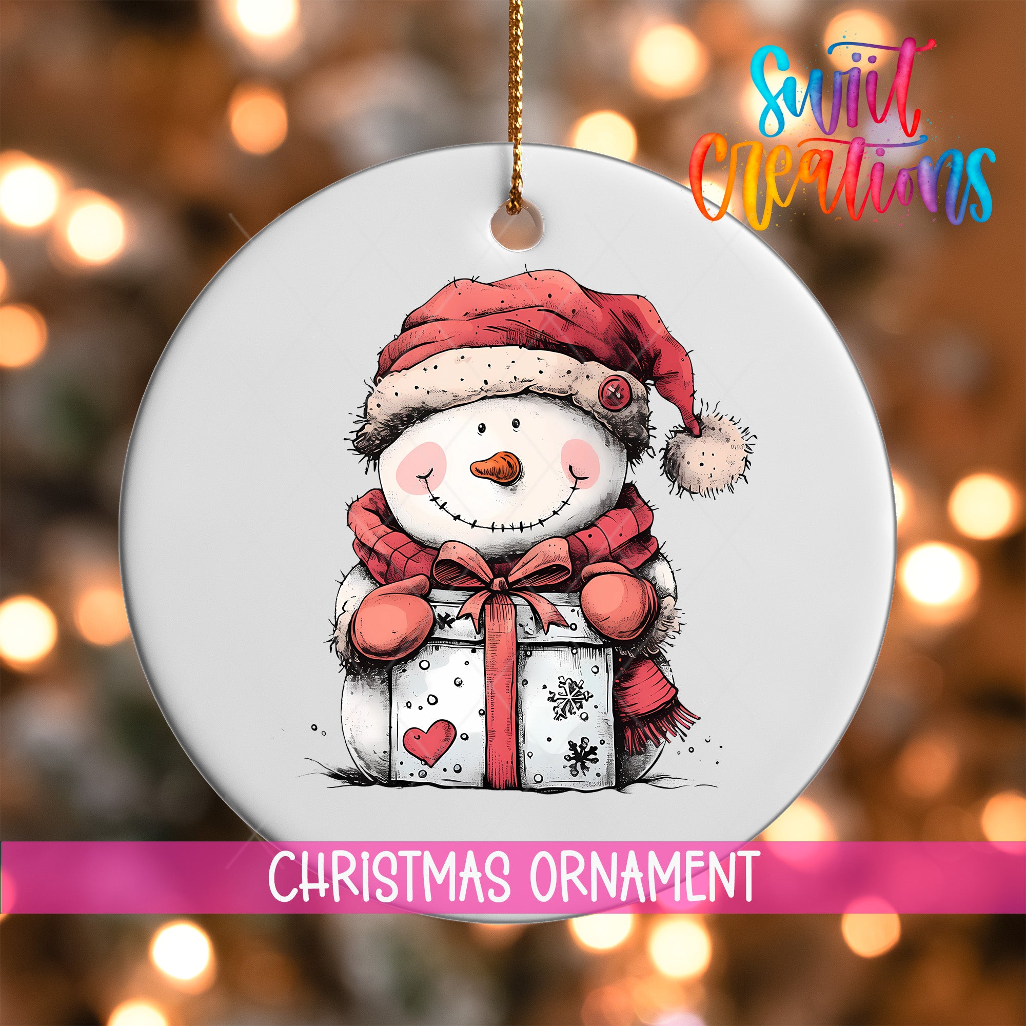 A white Christmas ornament with a snowman figure holding a gift box, set against a blurred background with Christmas lights.