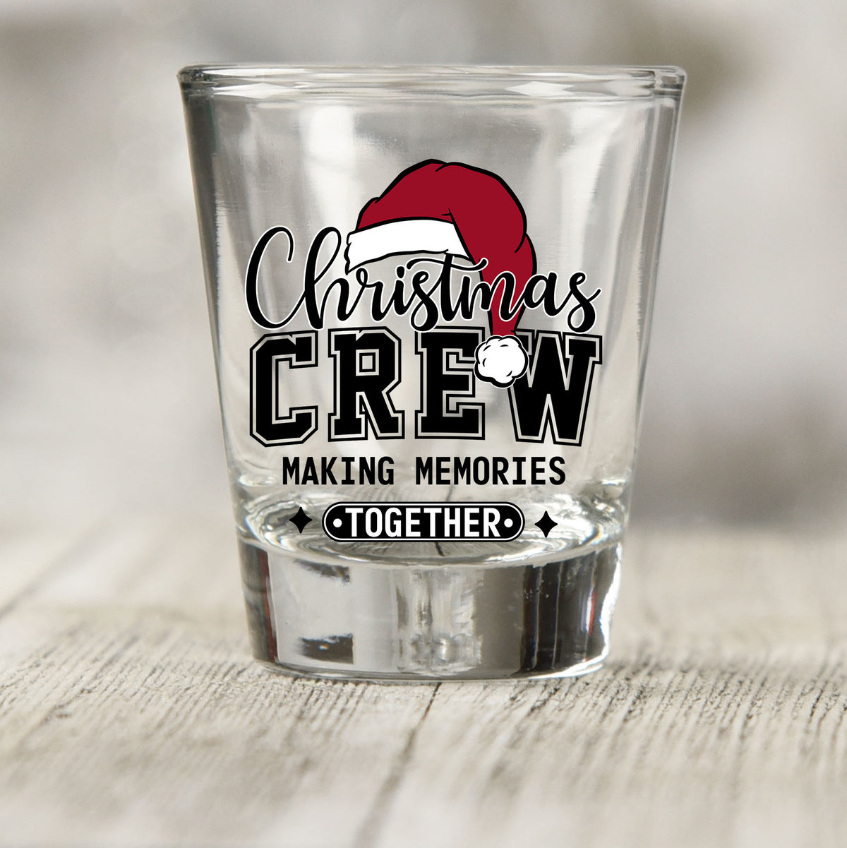 Christmas Crew Making Memories Together shot glass UV DTF transfer with a Santa hat on script lettering on a clear shot glass