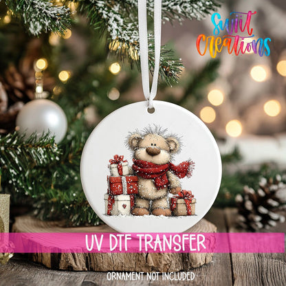 Teddy Bear with Gifts ornament UV DTF transfer on an ornament resting on a wood slice beside a Christmas tree