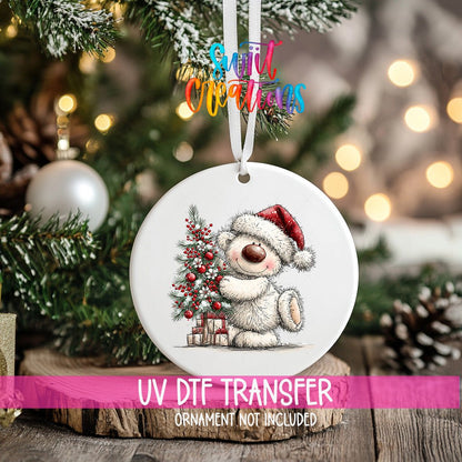 Christmas Tree Hug White Bear ornament UV DTF transfer on an ornament resting on a wood slice beside a Christmas tree