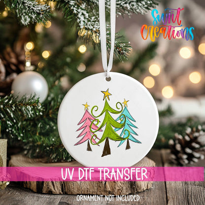 Whimsical Christmas Trees ornament UV DTF transfer on an ornament resting on a wood slice beside a Christmas tree