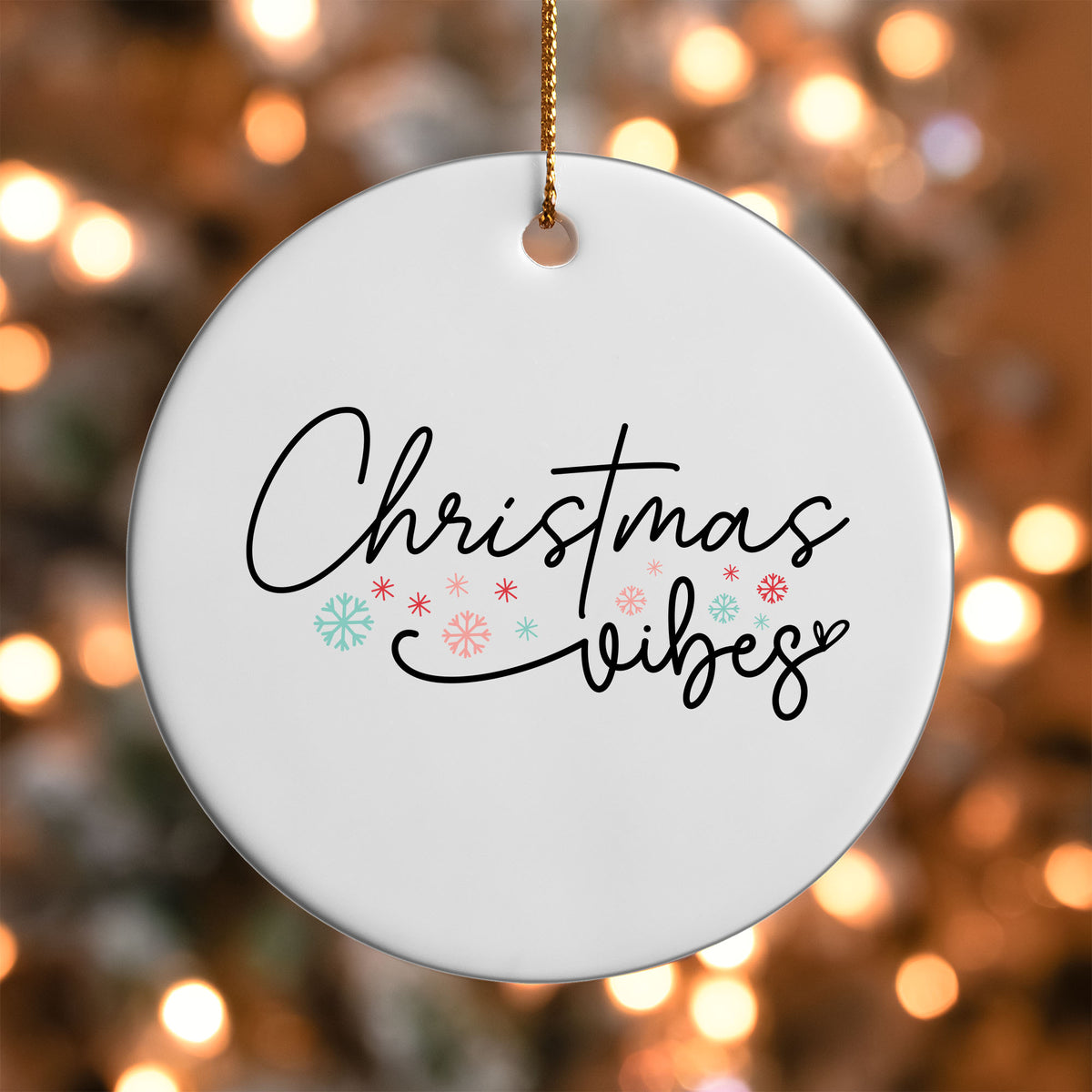 Christmas Vibes ornament UV DTF transfer on a round white ornament with a bokeh light background