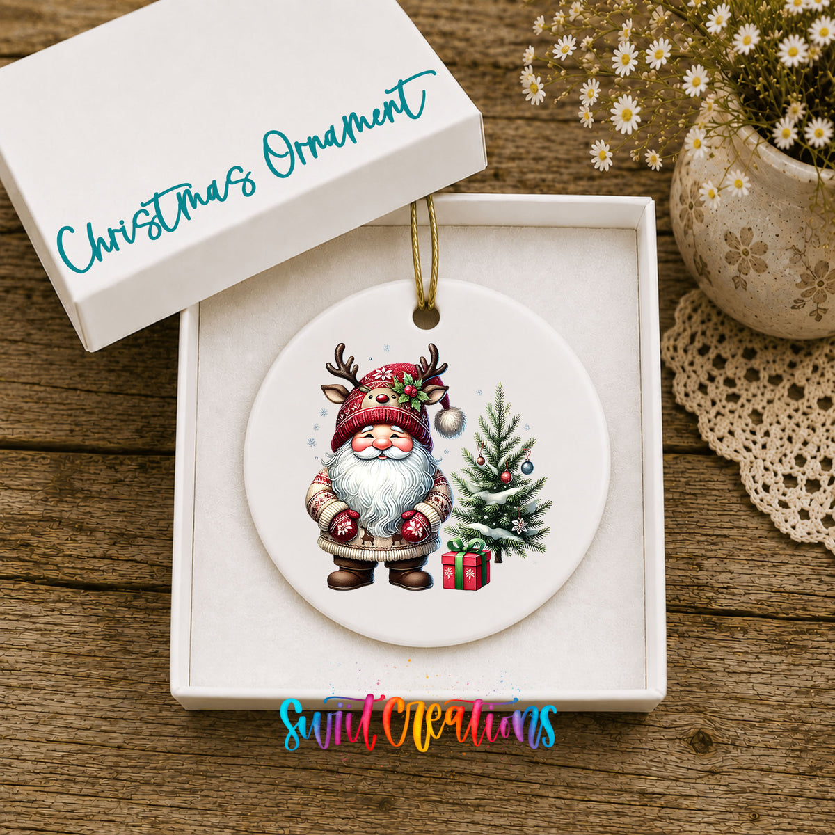 Santa beside a Christmas tree and wrapped gift ceramic Christmas ornament displayed in the included gift box