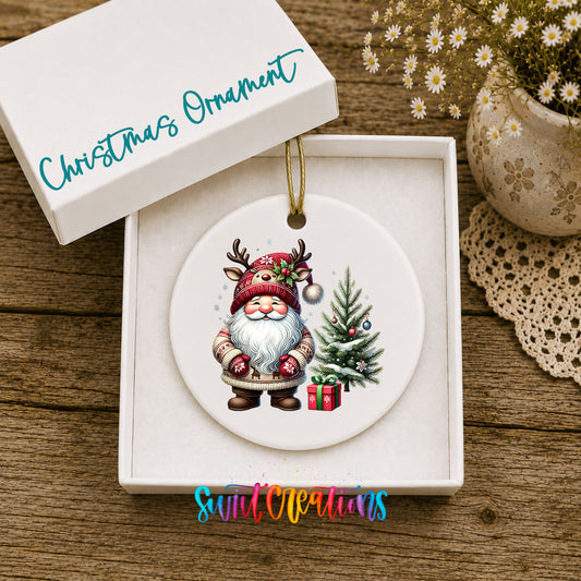 Santa beside a Christmas tree and wrapped gift ceramic Christmas ornament displayed in the included gift box