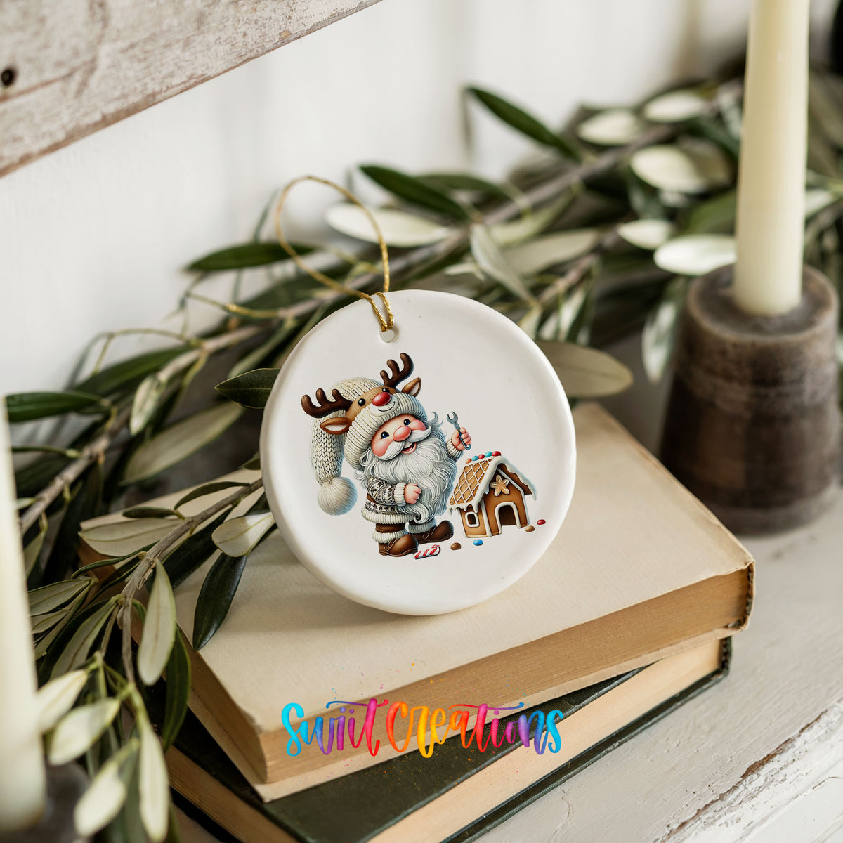 Santa decorating a gingerbread house ceramic Christmas ornament styled on books with holiday greenery