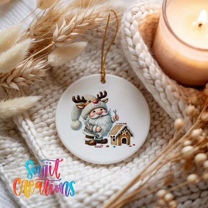 Santa decorating a gingerbread house ceramic Christmas ornament styled beside a candle and cozy knit blanket