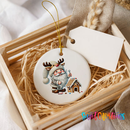 Santa decorating a gingerbread house ceramic Christmas ornament displayed in a rustic wooden gift crate