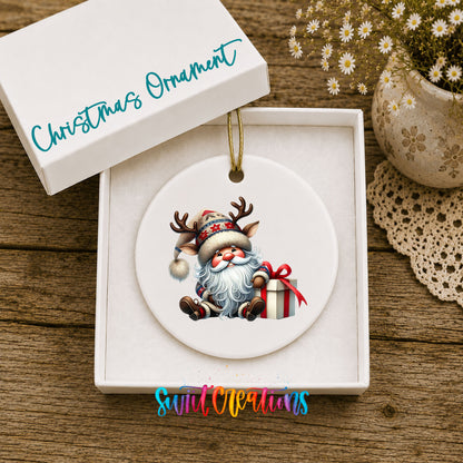 Santa sitting beside a wrapped Christmas gift ceramic Christmas ornament displayed in the included gift box