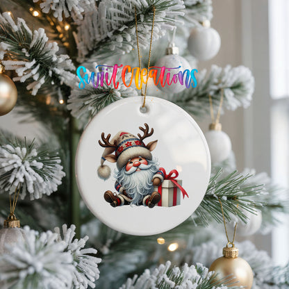 Santa sitting beside a wrapped Christmas gift ceramic Christmas ornament hanging on a frosted Christmas tree