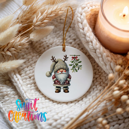 Round ceramic Christmas ornament featuring Santa standing beneath Christmas mistletoe, styled beside a candle and cozy knit blanket