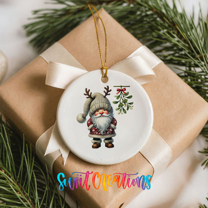 Round ceramic Christmas ornament featuring Santa standing beneath Christmas mistletoe, placed on a wrapped Christmas gift