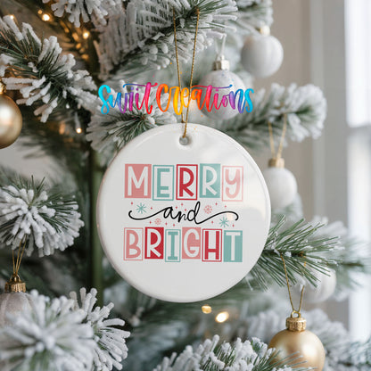 Round ceramic Christmas ornament featuring pastel block-letter Merry and Bright holiday typography, hanging on a frosted Christmas tree