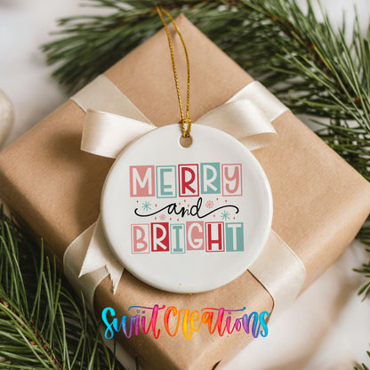 Round ceramic Christmas ornament featuring pastel block-letter Merry and Bright holiday typography, placed on a wrapped Christmas gift