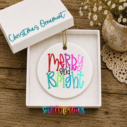 Round ceramic Christmas ornament featuring colorful hand-lettered Merry and Bright holiday typography, displayed in the included gift box