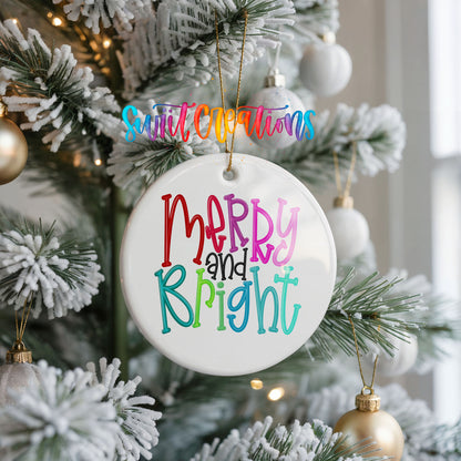 Round ceramic Christmas ornament featuring colorful hand-lettered Merry and Bright holiday typography, hanging on a frosted Christmas tree