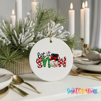 Round ceramic Christmas ornament featuring playful red and black Let It Snow holiday typography, styled with elegant holiday table decor