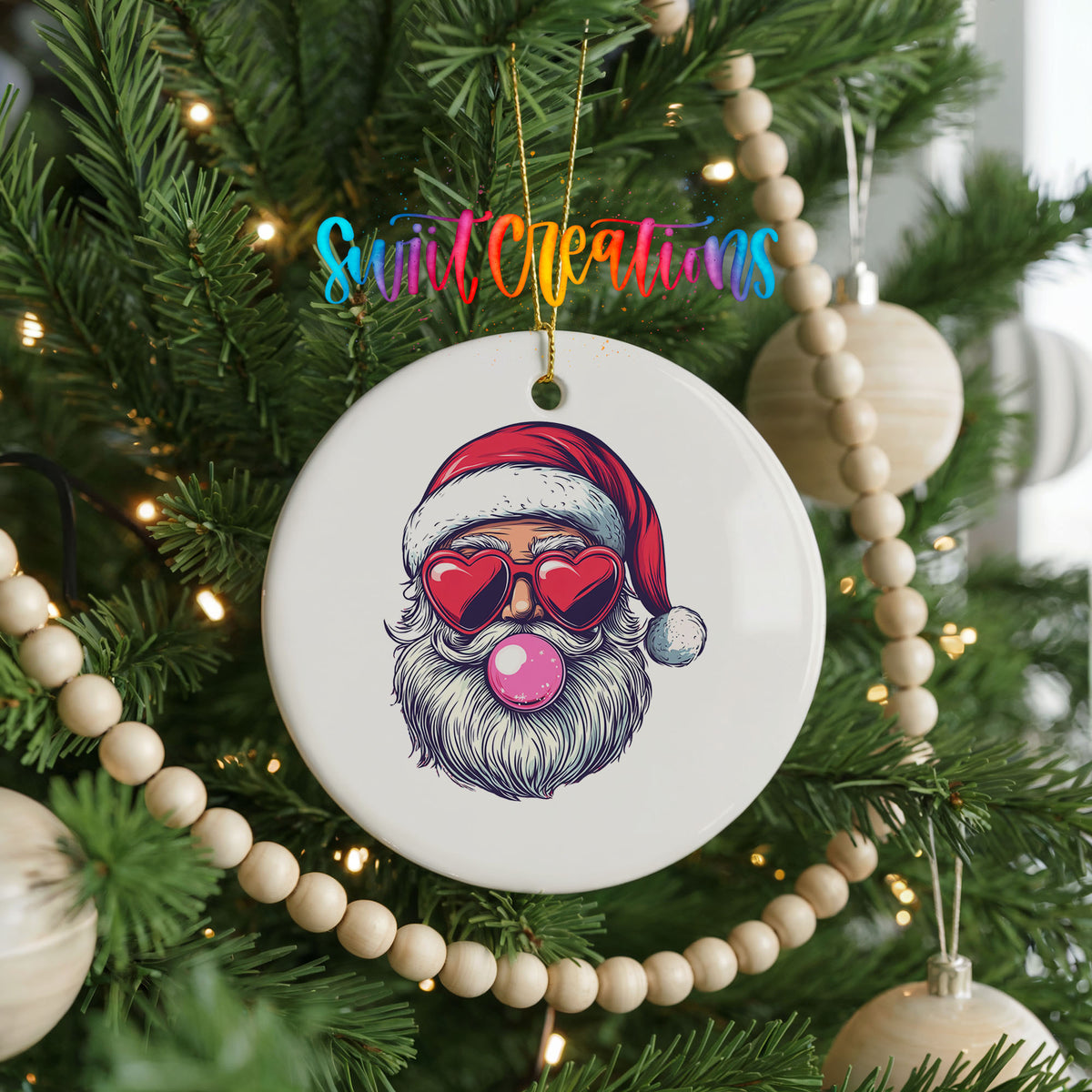 Round ceramic Christmas ornament featuring retro Santa wearing sunglasses and blowing pink bubblegum, hanging on a decorated Christmas tree