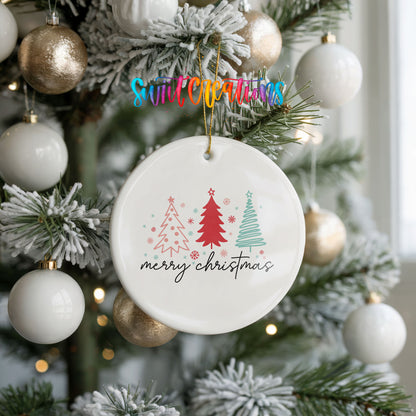 Round ceramic Christmas ornament featuring minimalist red and mint Christmas trees with Merry Christmas script, hanging on a frosted holiday tree