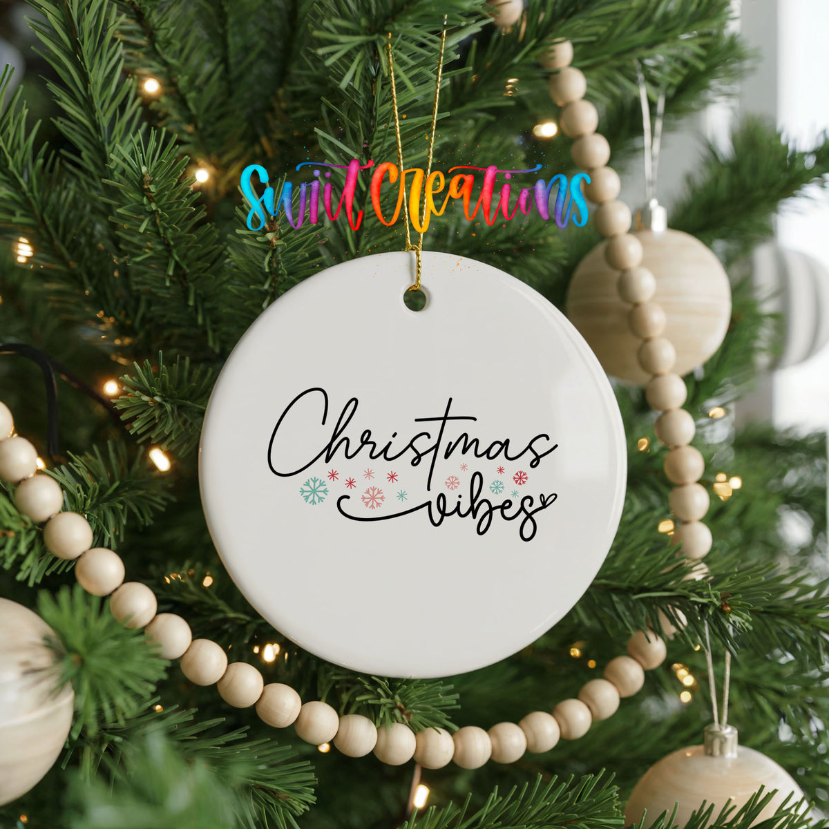 Round ceramic Christmas ornament featuring delicate Christmas Vibes script with small colorful holiday accents, hanging on a decorated Christmas tree