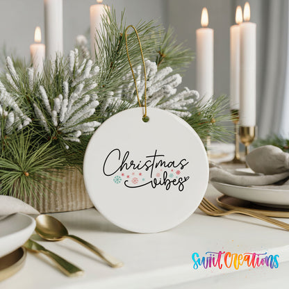 Round ceramic Christmas ornament featuring delicate Christmas Vibes script with small colorful holiday accents, styled with elegant holiday table decor