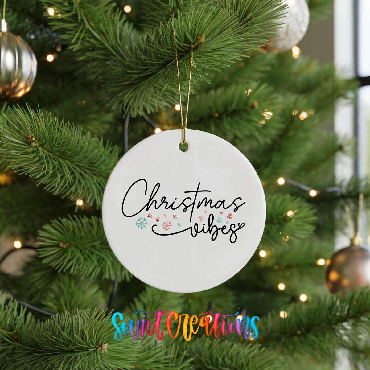 Round ceramic Christmas ornament featuring delicate Christmas Vibes script with small colorful holiday accents, hanging on a green Christmas tree