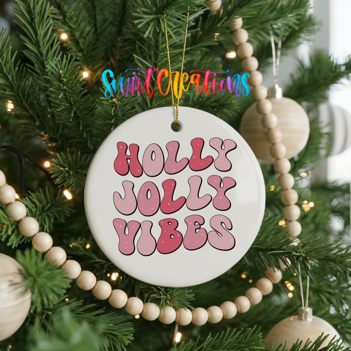 Round ceramic Christmas ornament featuring pink retro Holly Jolly Vibes typography, hanging on a decorated Christmas tree