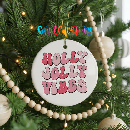 Round ceramic Christmas ornament featuring pink retro Holly Jolly Vibes typography, hanging on a decorated Christmas tree