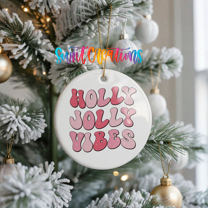 Round ceramic Christmas ornament featuring pink retro Holly Jolly Vibes typography, hanging on a frosted Christmas tree