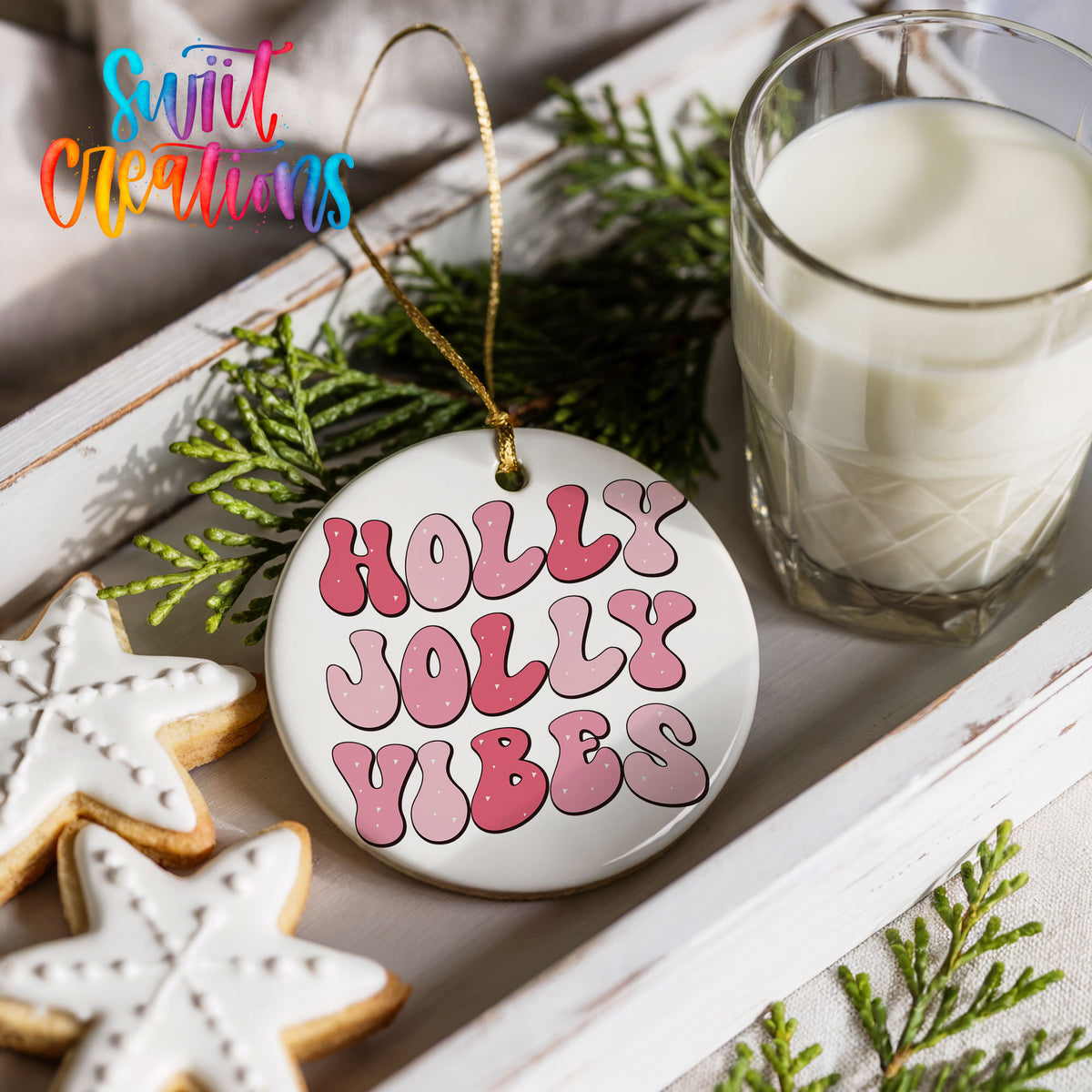 Round ceramic Christmas ornament featuring pink retro Holly Jolly Vibes typography, styled with cookies and milk
