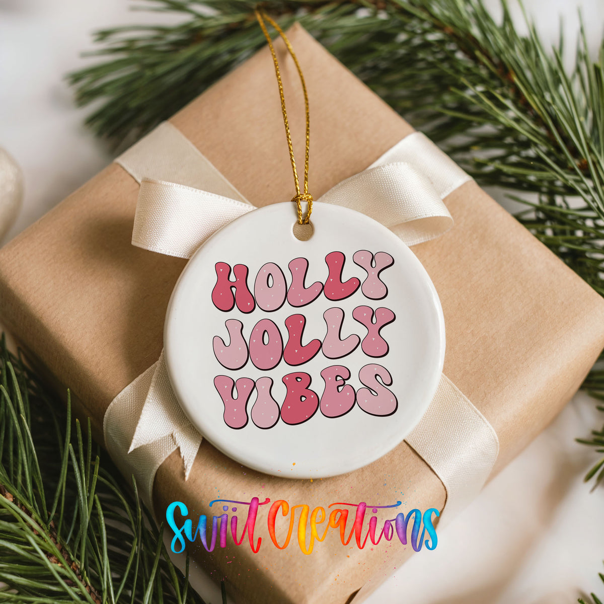 Round ceramic Christmas ornament featuring pink retro Holly Jolly Vibes typography, placed on a wrapped Christmas gift