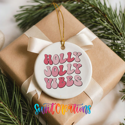 Round ceramic Christmas ornament featuring pink retro Holly Jolly Vibes typography, placed on a wrapped Christmas gift