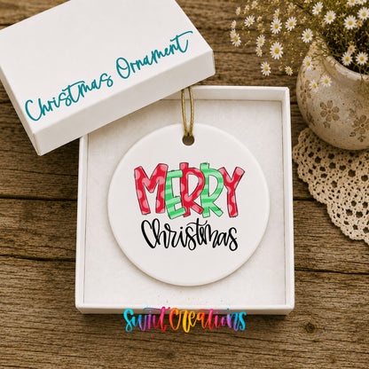 Round ceramic Christmas ornament featuring colorful patterned Merry Christmas typography, displayed in the included gift box