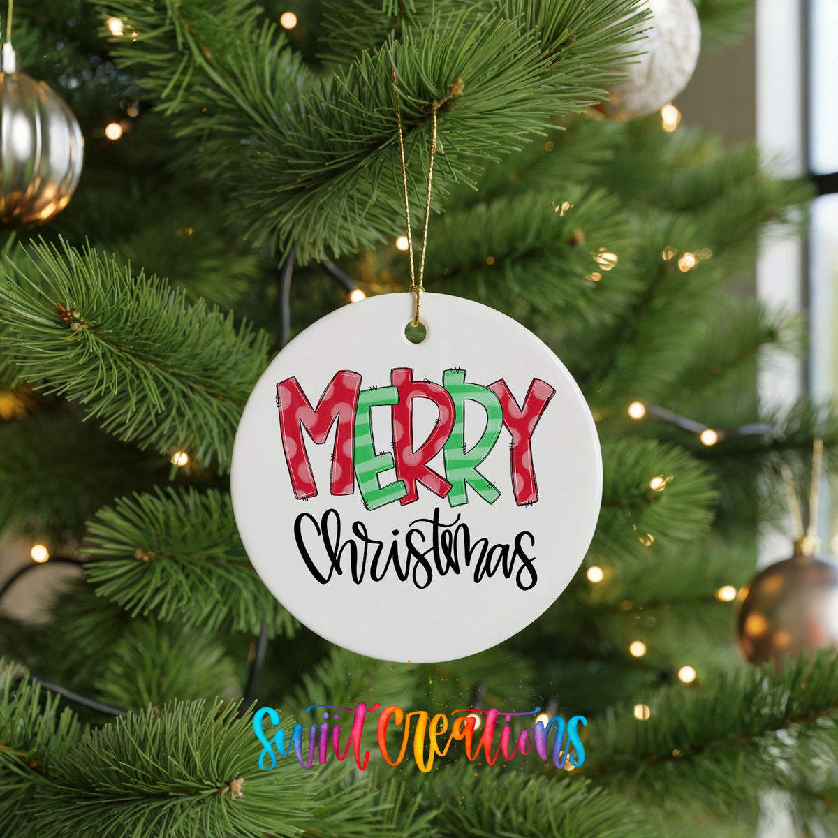Round ceramic Christmas ornament featuring colorful patterned Merry Christmas typography, hanging on a green Christmas tree