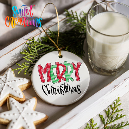 Round ceramic Christmas ornament featuring colorful patterned Merry Christmas typography, styled with cookies and milk