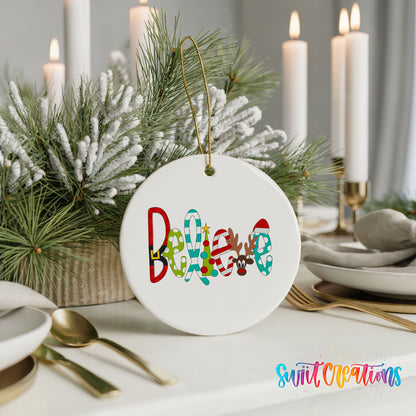 Round ceramic Christmas ornament featuring colorful whimsical Believe holiday lettering, styled with elegant holiday table decor