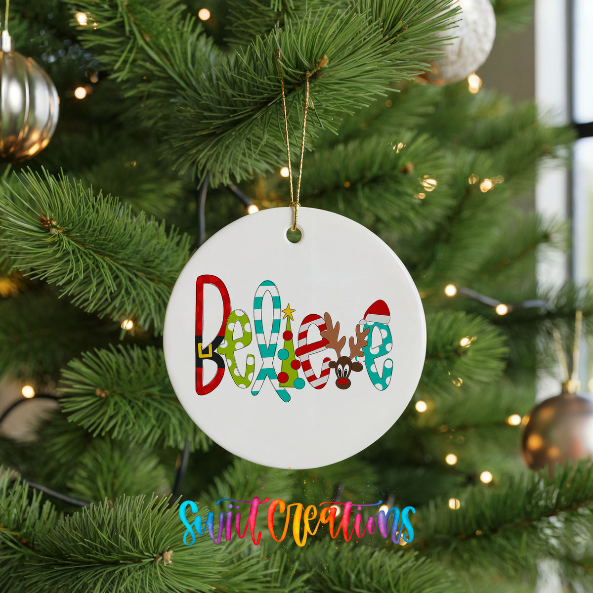 Round ceramic Christmas ornament featuring colorful whimsical Believe holiday lettering, hanging on a green Christmas tree