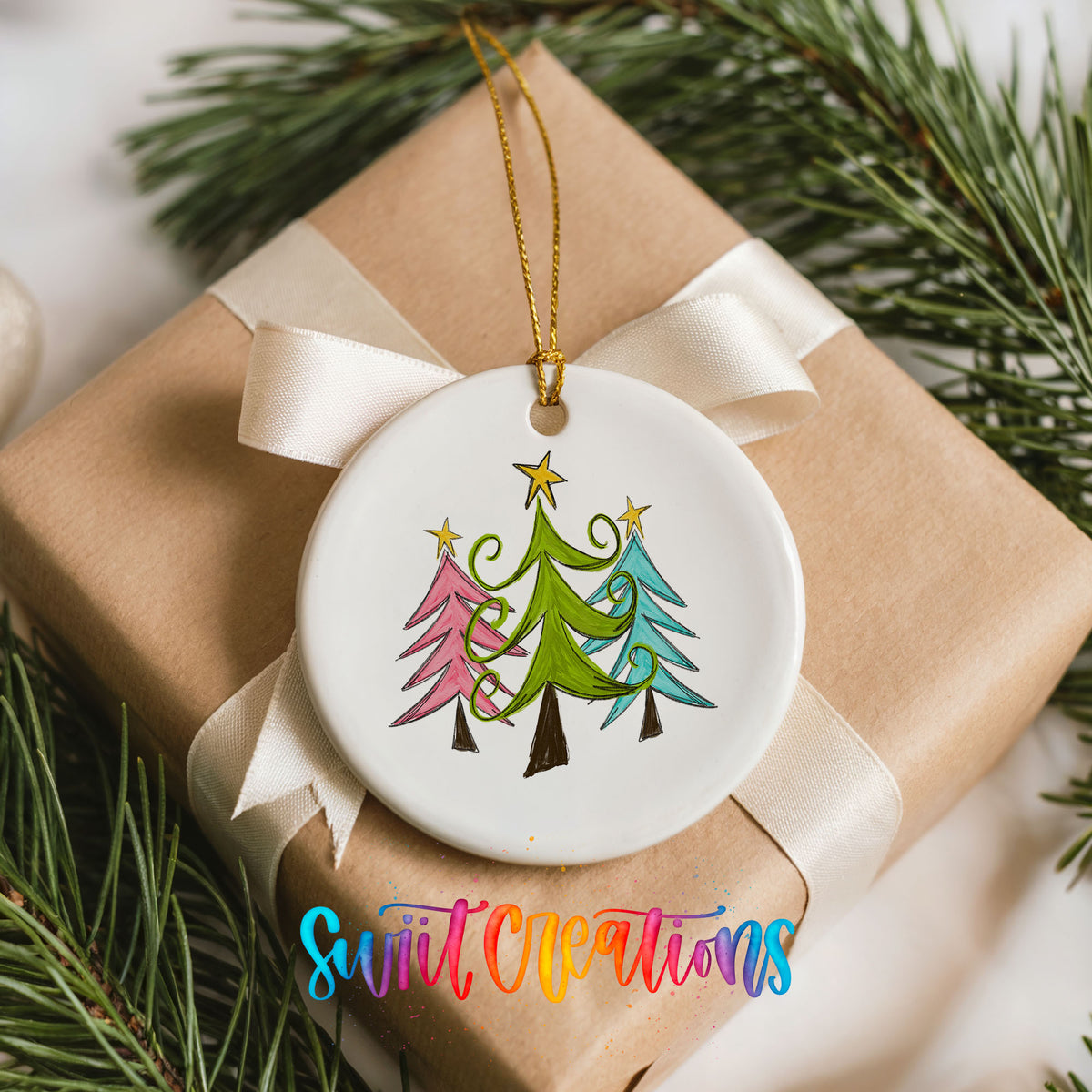 Round ceramic Christmas ornament featuring three colorful whimsical Christmas trees, placed on a wrapped Christmas gift