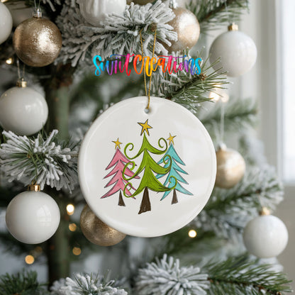 Round ceramic Christmas ornament featuring three colorful whimsical Christmas trees, hanging on a frosted holiday tree