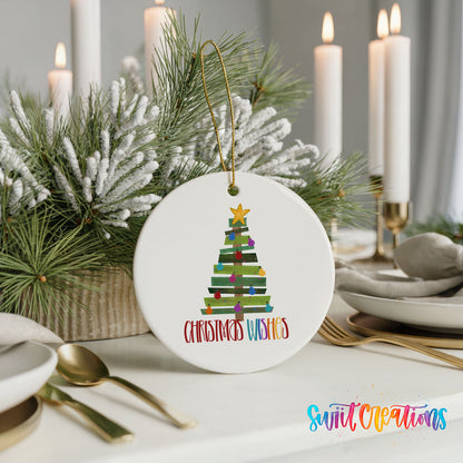 Round ceramic Christmas ornament featuring colorful pallet-style Christmas tree with Christmas Wishes lettering, styled with elegant holiday table decor
