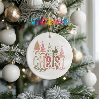 Round ceramic Christmas ornament featuring Merry Christmas typography with a pastel winter village and trees, hanging on a frosted holiday tree