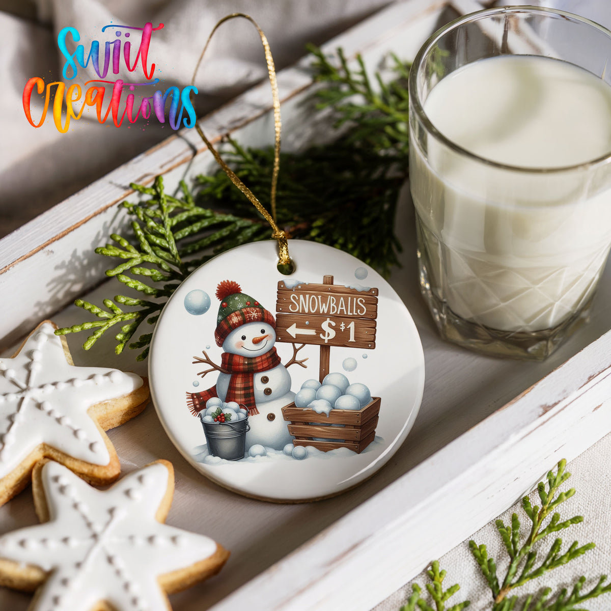 Round ceramic Christmas ornament featuring cheerful snowman selling snowballs for five cents, styled with cookies and milk