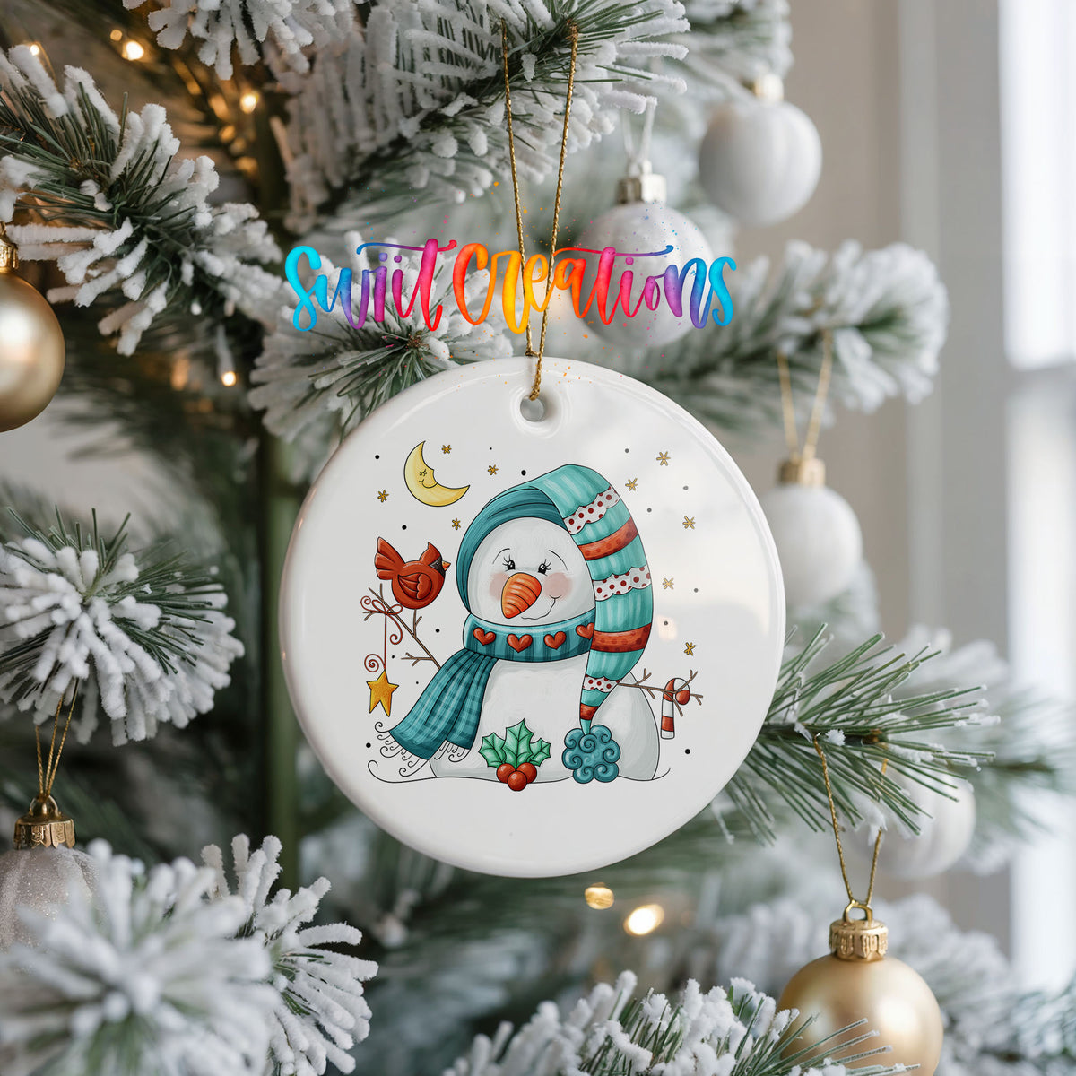 Round ceramic Christmas ornament featuring cozy snowman holding a bright red cardinal beneath a winter moon, hanging on a frosted Christmas tree