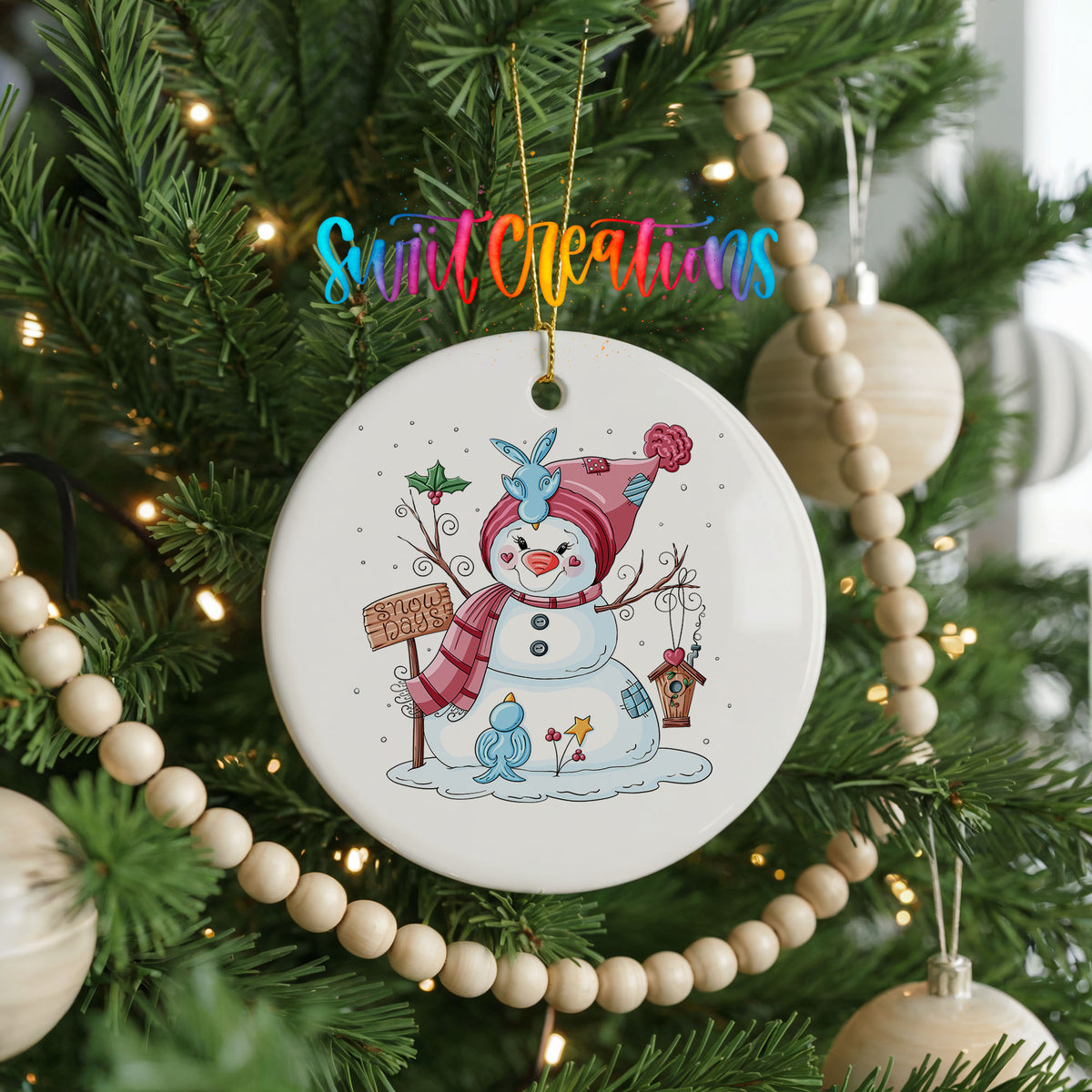 Round ceramic Christmas ornament featuring playful snowman dressed for a colorful winter snow day, hanging on a decorated Christmas tree