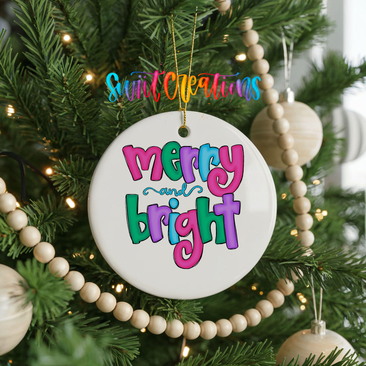 Round ceramic Christmas ornament featuring bright groovy Merry and Bright lettering in pink teal and purple, hanging on a decorated Christmas tree
