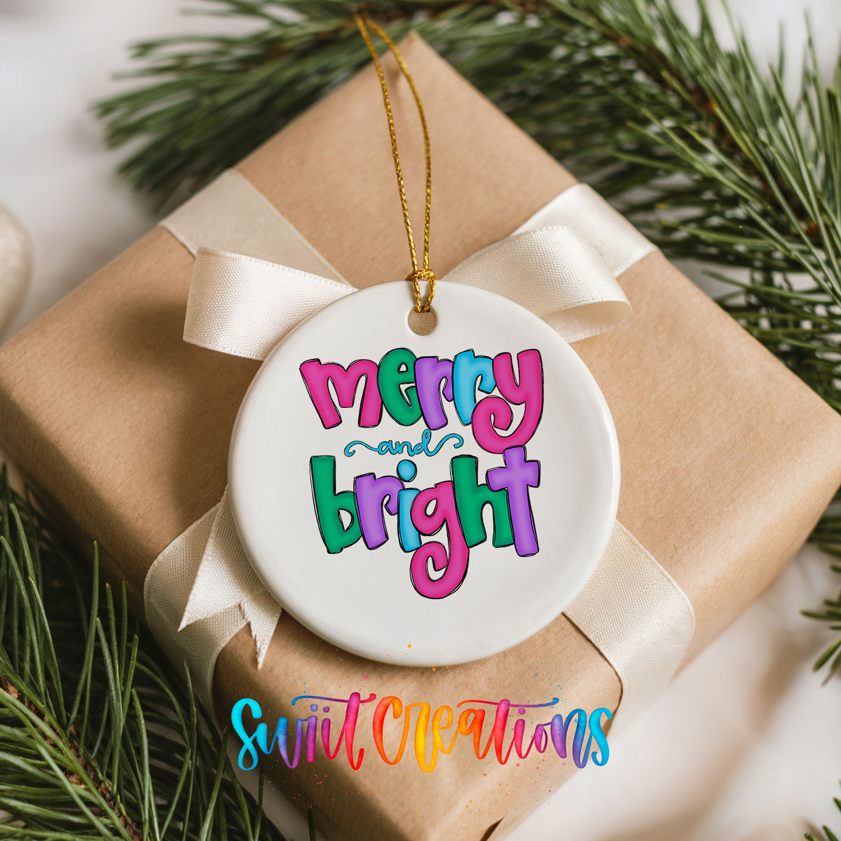 Round ceramic Christmas ornament featuring bright groovy Merry and Bright lettering in pink teal and purple, placed on a wrapped Christmas gift